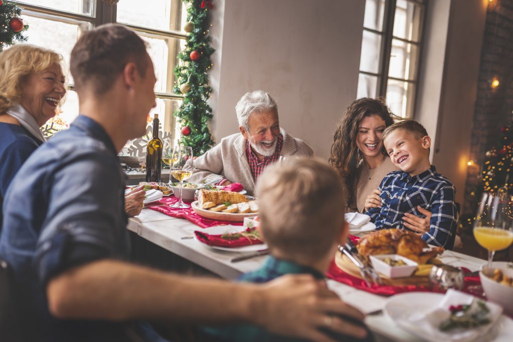 Beautiful happy family gathered around the table, having Christmas dinner, enjoying their time together and the winter holiday season