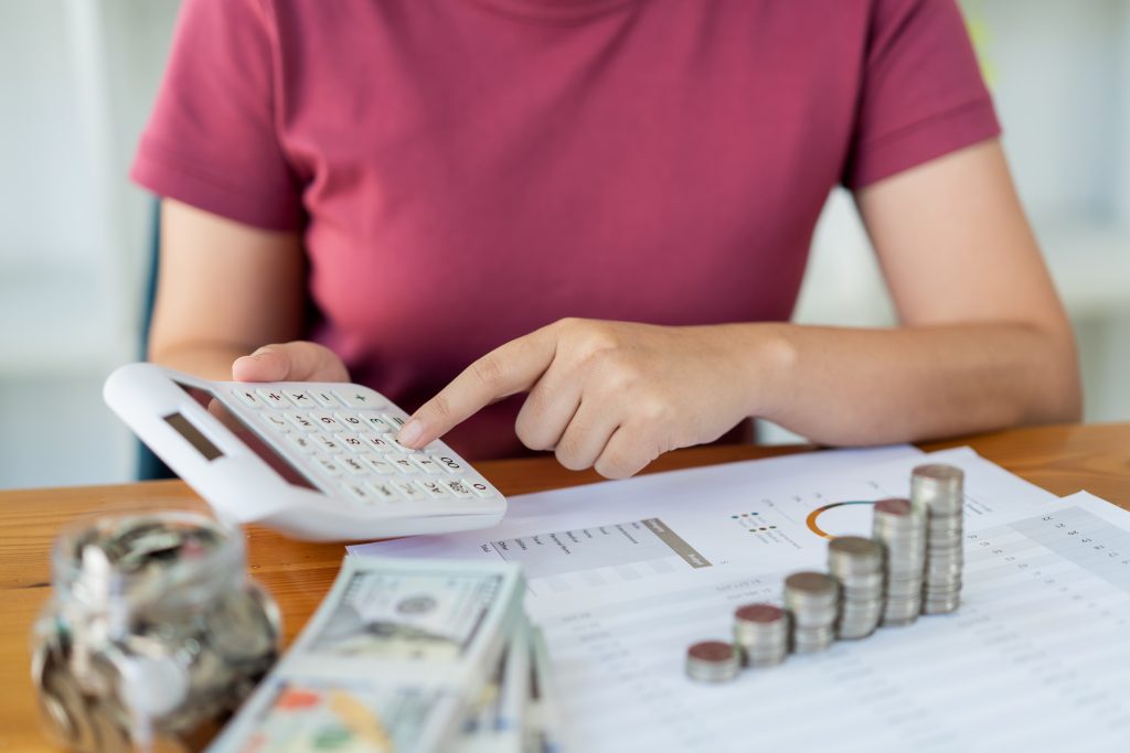 Saving concept the woman in a red top calculating monthly expense and income by using the calculator.