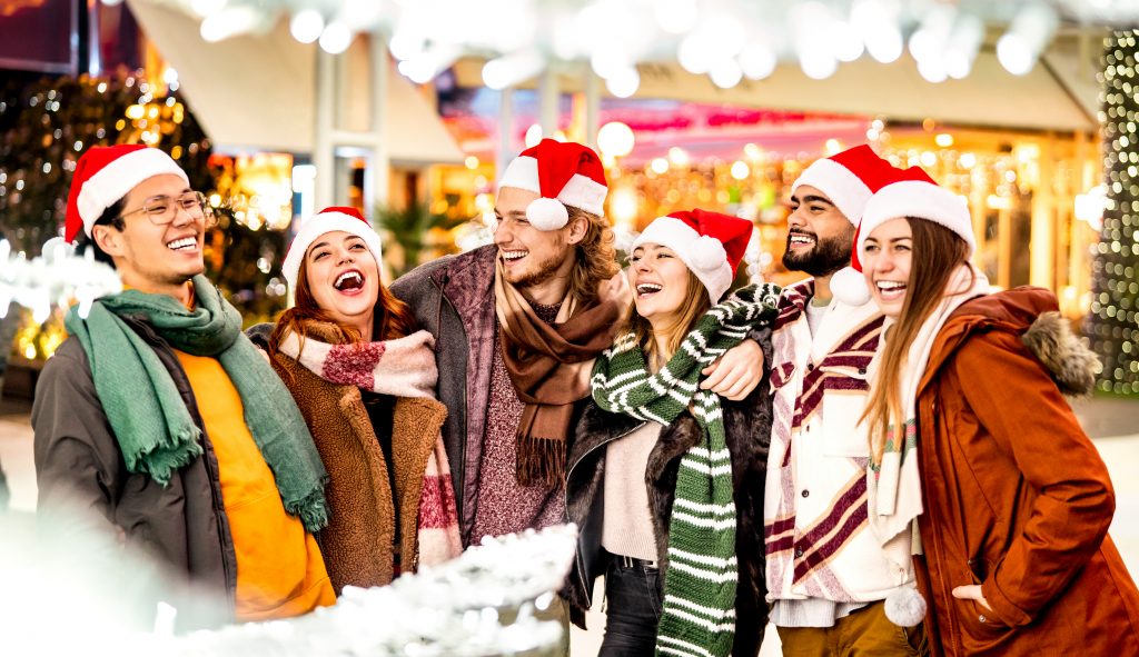 Happy friends group walking at city on Christmas vacation - Winter life style concept with multicultural young people wearing red santa hats having fun holiday together outdoors - Warm bright filter