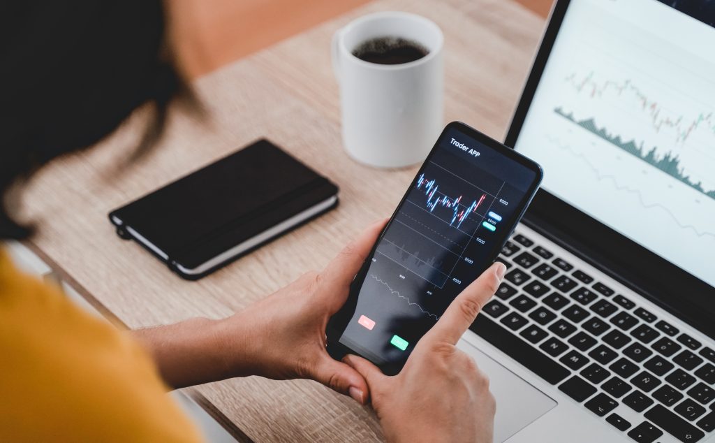 Trader business woman using trading stock market exchange app - Bitcoin, global economy concept - Focus on hands holding mobile phone