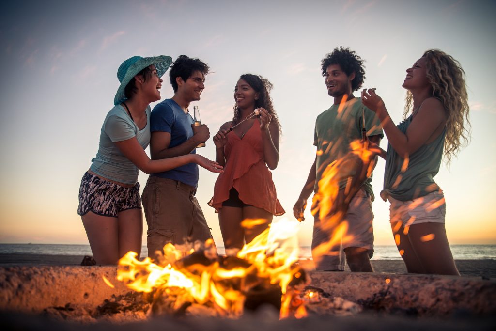 Multicultural group of friends partying on the beach - Young people celebrating during summer vacation, summertime and holidays concepts