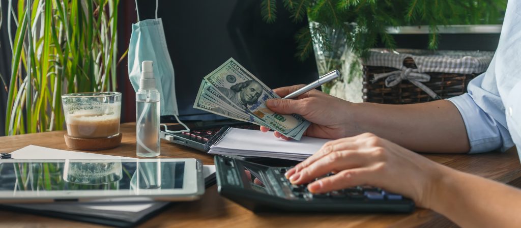 Home budget financial planning in crisis. Woman quarantined and working, planning home budget, lockdown covid 19. Business woman holding a pen and press calculator for calculating financial report,