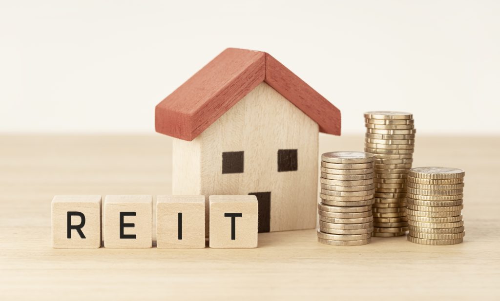 REIT Real estate investment trust concept. House model, money and wooden blocks with text