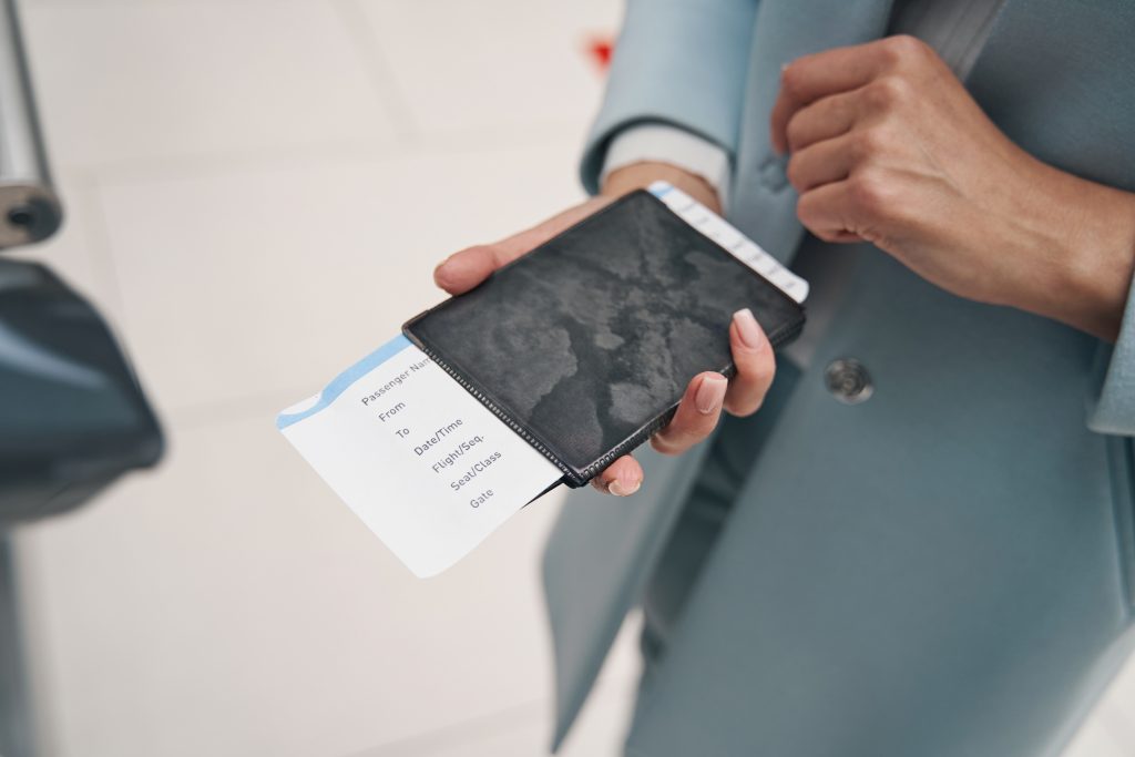 Cropped photo of air traveler holding passport and boarding ticket in her hand