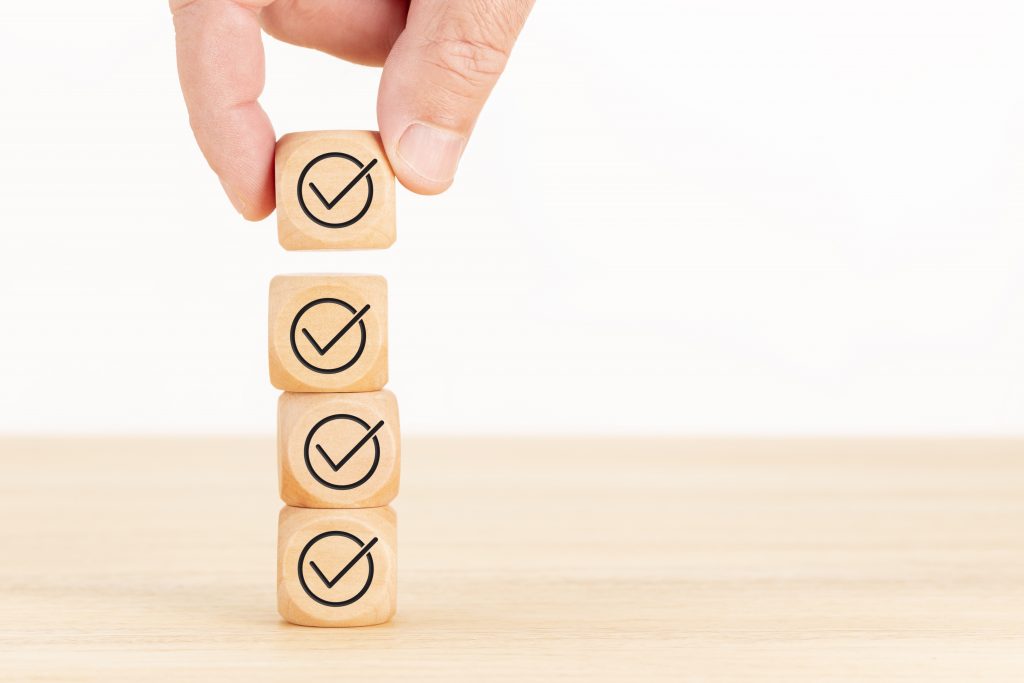 Checking or checklist concept. Hand picked wooden cube block with check icon stacked on wooden table. Copy space