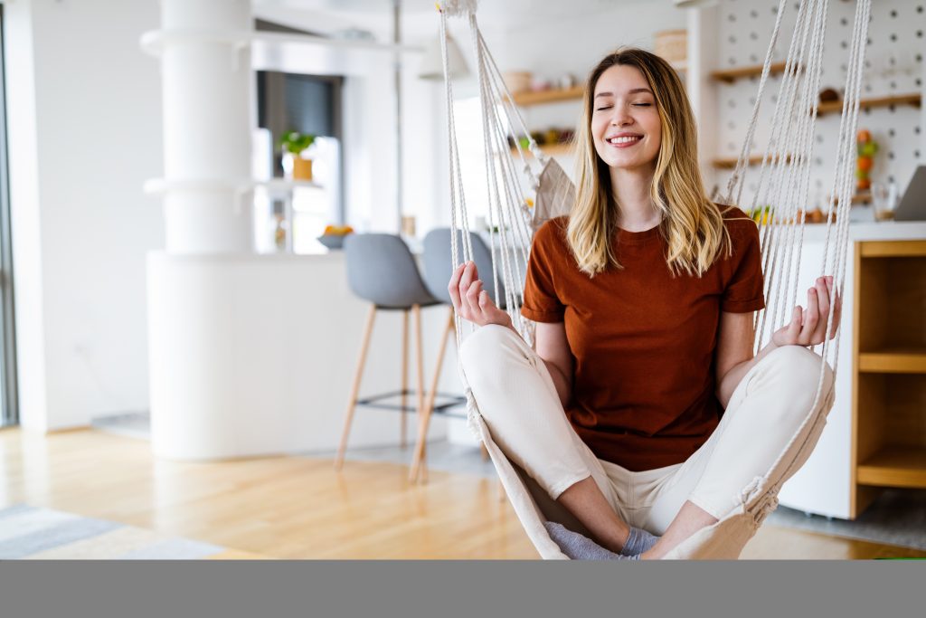 Peaceful girl practicing yoga at home relaxing with eyes closed. Stress free concept