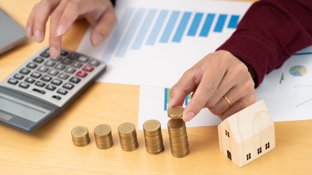 Property investment and house mortgage financial concept, hand of a businessman who is stacking coins for Real estate investment, saving for buying for housing or speculation