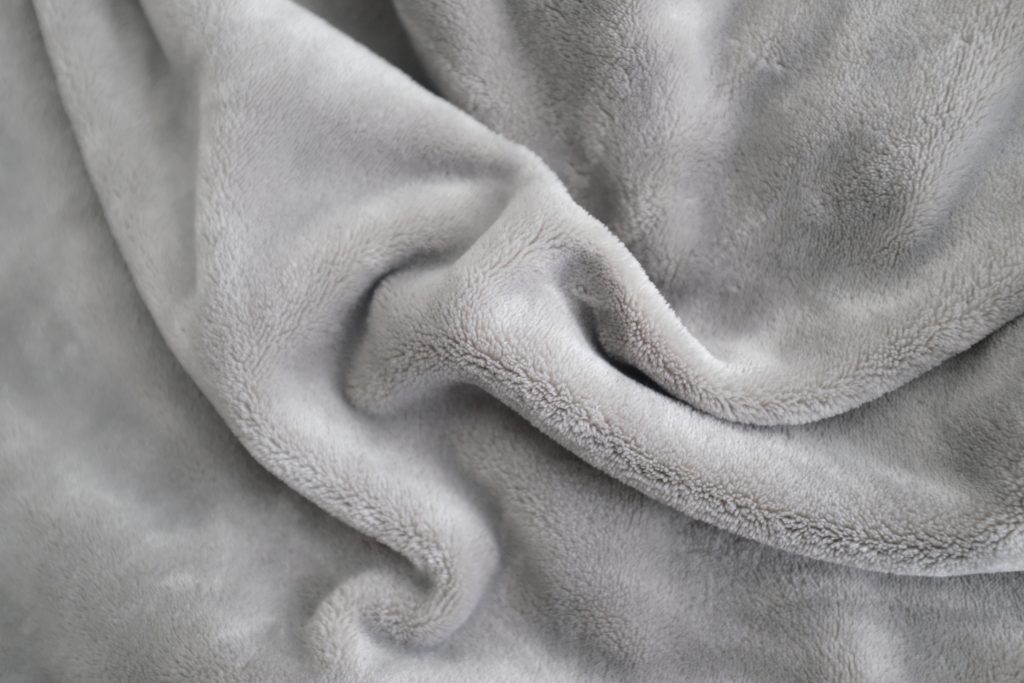 A closeup shot of a gray, soft and smooth texture throw blanket -- great for photo manipulation and 3d rendering material