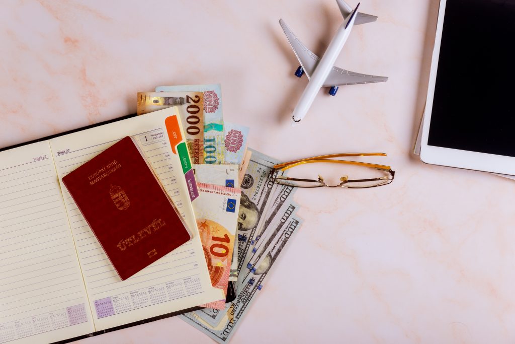 Travel booking flights reservation on the devices tablet touch pad with Hungarian passports and dollar banknotes Planning a trip