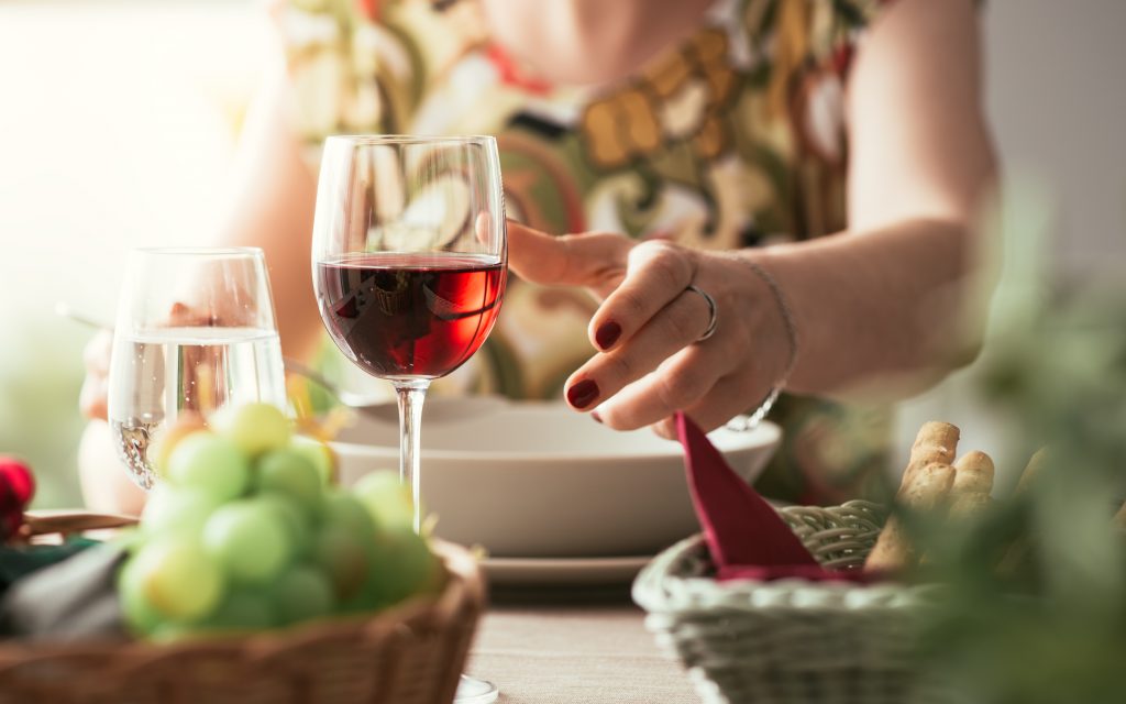 Woman having lunch at the restaurant, she is taking a glass of red wine, fine dining and lifestyle concept