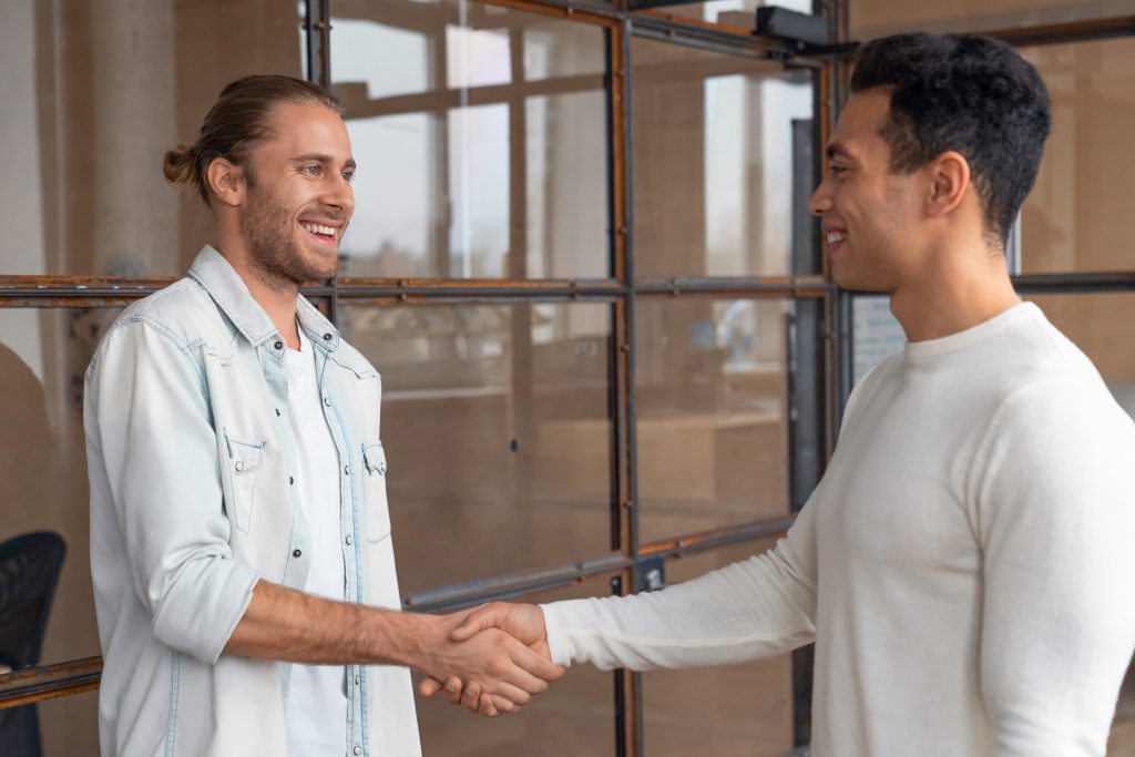 Young businessman shaking hands with male colleague after meeting in boardroom. Business handshake after successful meeting