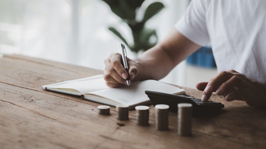 A person is holding coins in five rows from low to high, he is accounting for income and expenses and dividing her savings. Concept of saving money and investing it to grow money.