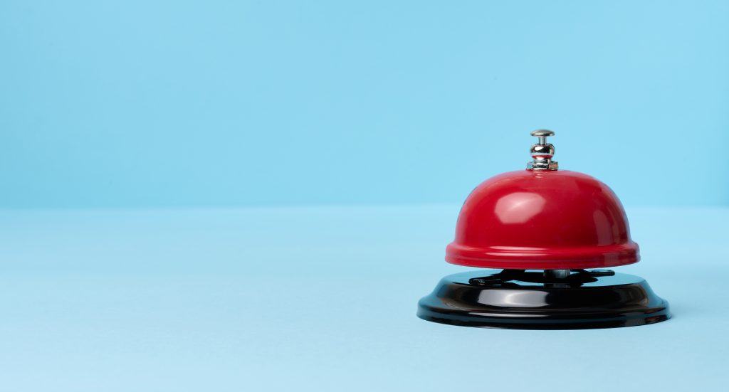Metallic red bell to call staff on a blue background, copy space