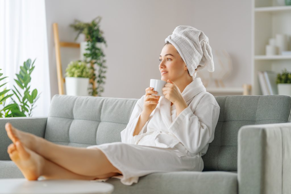 Happy woman is relaxing and drinking tea after a bath.