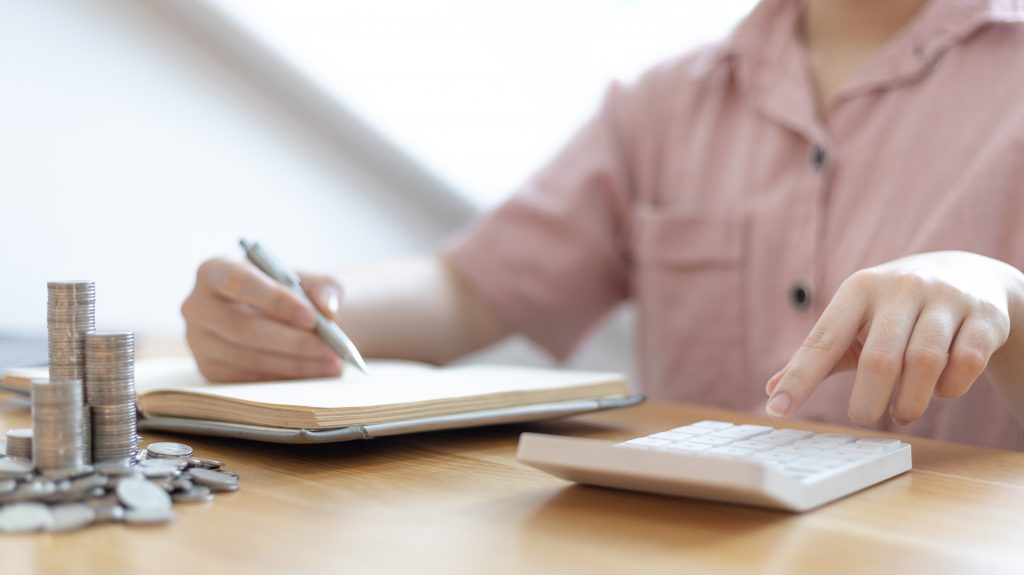 Dollar coins arranged in a slope graph, Blurred image of a businesswoman pressing a calculator, Take a notebook to record information, Saving money for business growth, Save money.