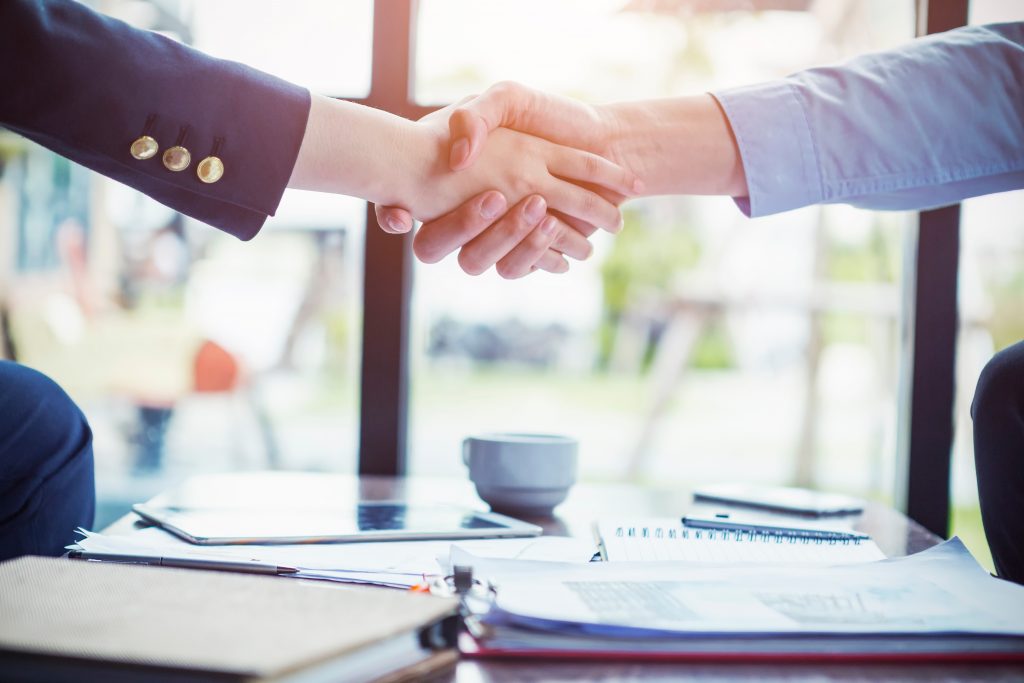 Business people make a deal with handshake at office or cafe. Success business concept.